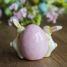 Load image into Gallery viewer, Cerami Bunnies Holding Pink Egg Ornament